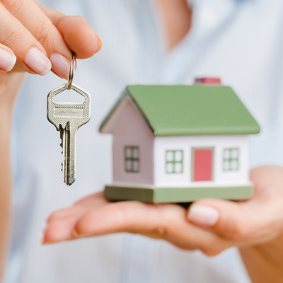 Person holding a key and small house