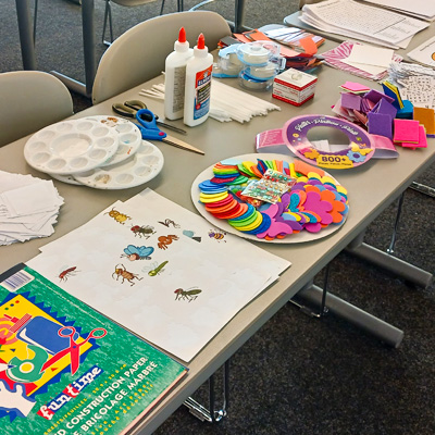 Supplies, including stickers, Christmas ornaments, construction paper, glue, provided for the ‘Create a Spring Ornament’ activity